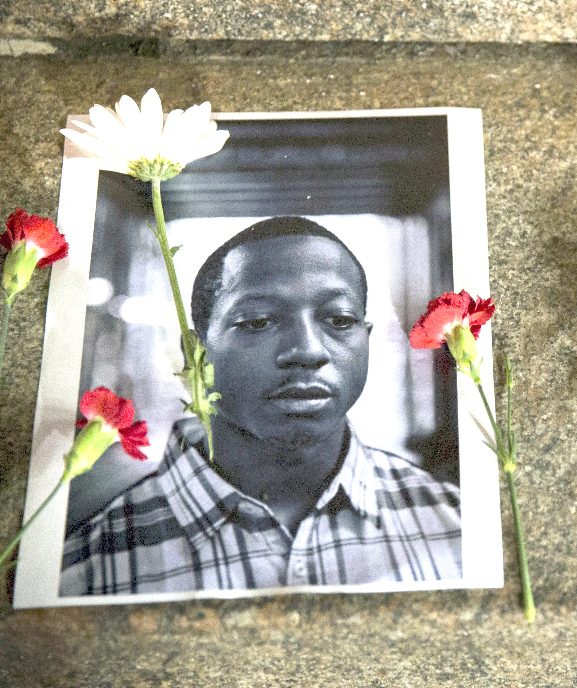 Flowers rest on top of pictures of Kalief Browder in New York June 11, 2015. New York City Mayor Bill de Blasio on Monday vowed to push reforms at the city's troubled Rikers Island prison complex after the reported weekend suicide of the 22-year-old Browder who had been held there for three years without being convicted of a crime. REUTERS/Lucas Jackson