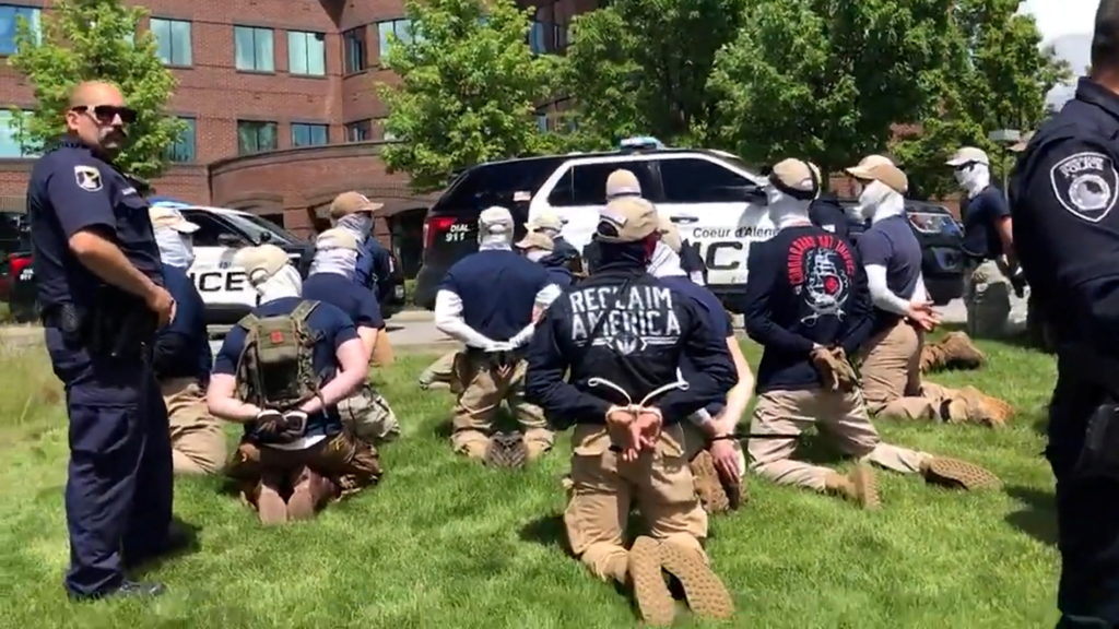 Police officers guard a group of men, who police say are among 31 arrested for conspiracy to riot and are affiliated with the white nationalist group Patriot Front, after they were found in the rear of a U Haul van in the vicinity of a North Idaho Pride Alliance LGBTQ+ event in Coeur d'Alene, Idaho, U.S. June 11, 2022 in this still image obtained from a social media video. North Country Off Grid/Youtube/via REUTERS  THIS IMAGE HAS BEEN SUPPLIED BY A THIRD PARTY. MANDATORY CREDIT. NO RESALES. NO ARCHIVES.